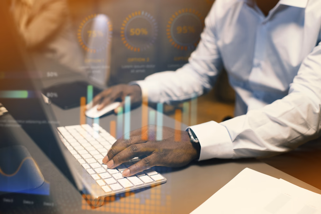 Hands typing on a keyboard beside financial charts